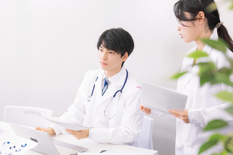 医師役の日本人モデルが資料を確認するストック写真